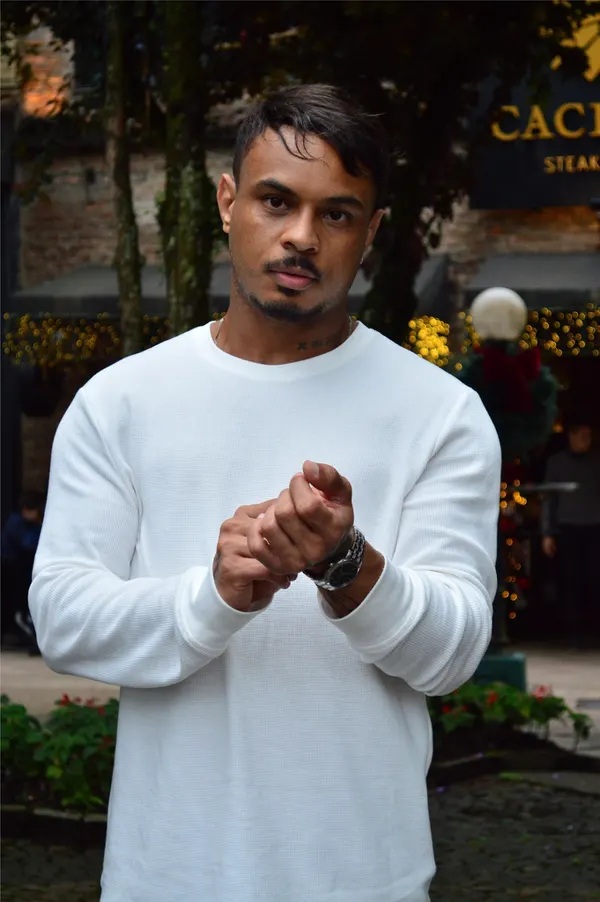 Luiz Medeiros, de blusa branca, em uma rua arborizada